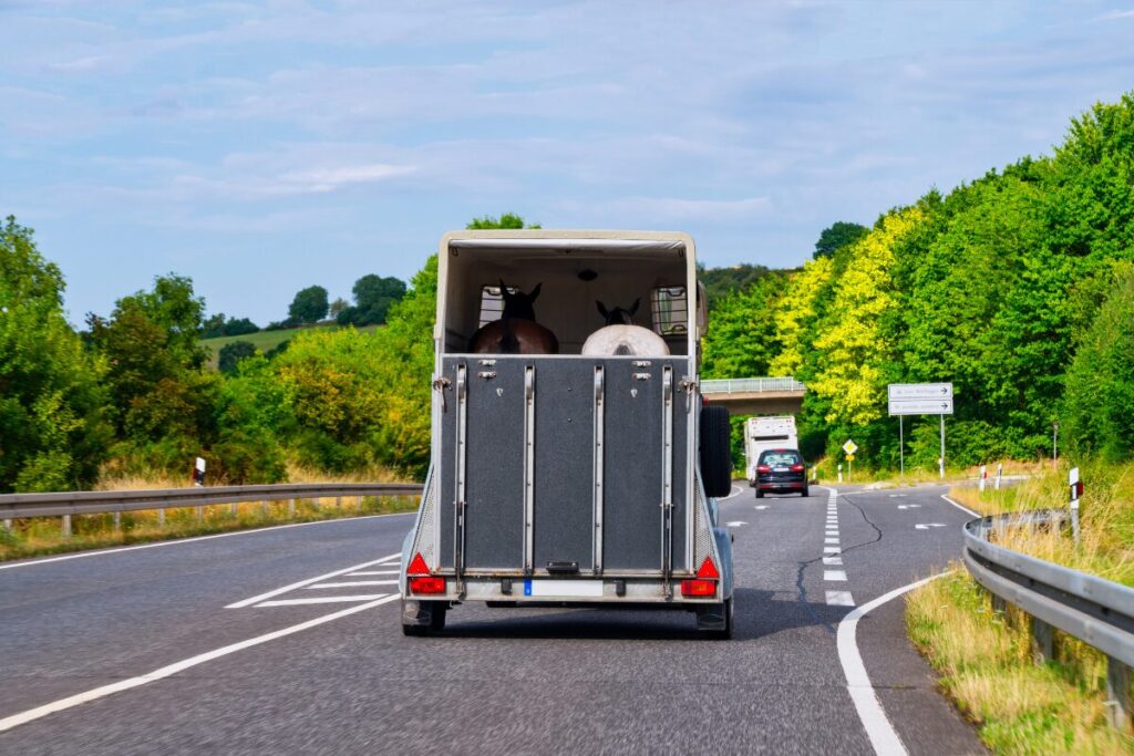 Enclosed trailer travelling on a highway with its rear ramp door raised.